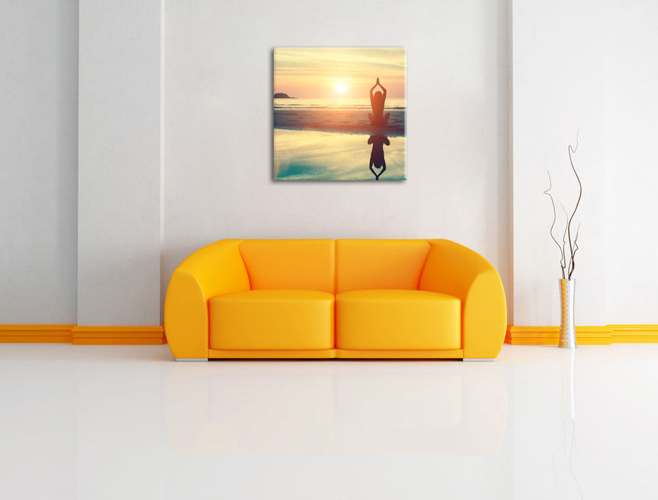 Frau in einer Yogapose am Strand Leinwandbild Quadratisch über Sofa