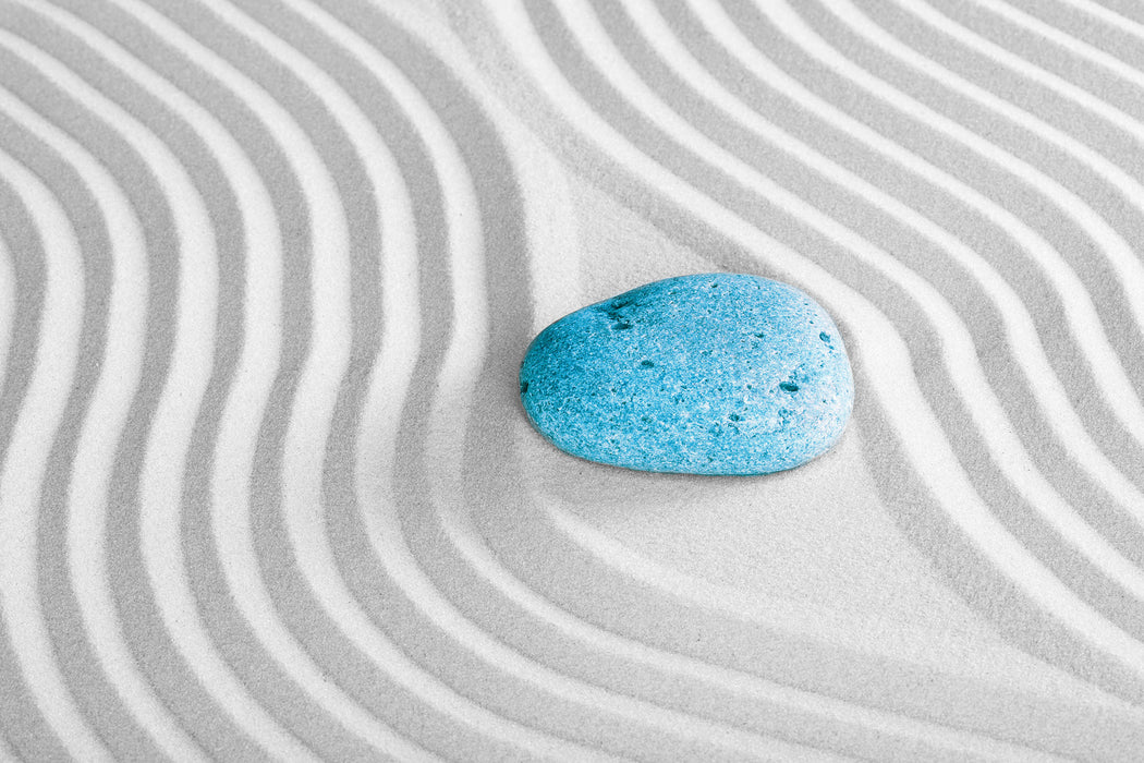 Ein Stein im Sand mit Wellenmuster, Glasbild