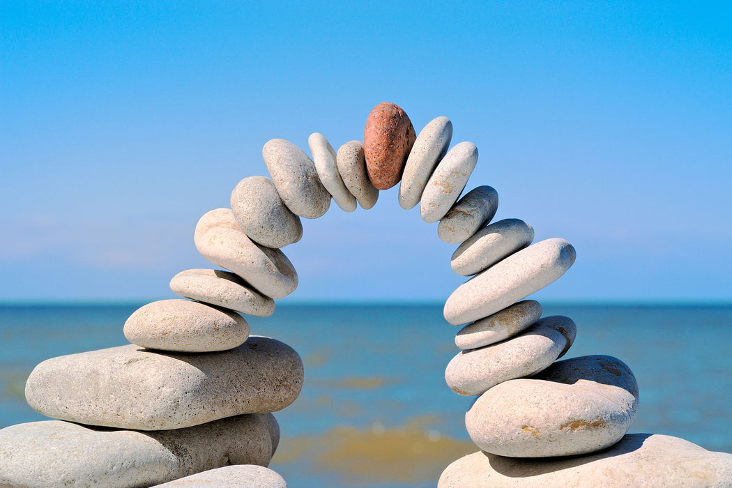 Brücke aus Zen Steinen am Meer, Glasbild