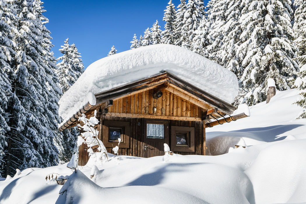 Verschneite Skihütte in Alpenwald, Glasbild