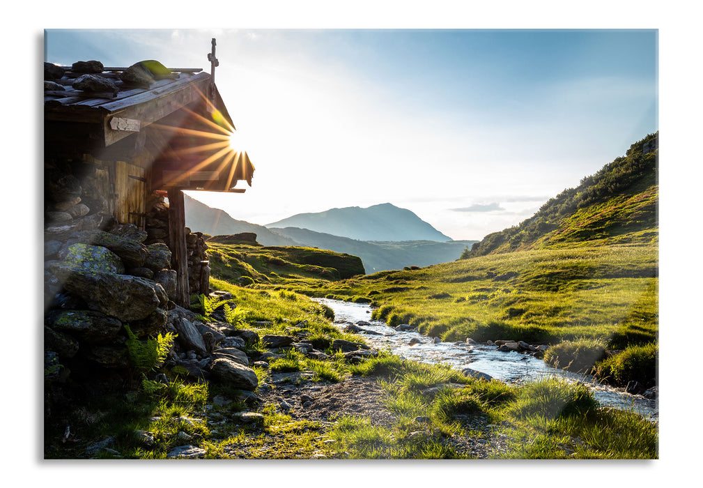 Almhütte am Bach bei Sonnenuntergang, Glasbild