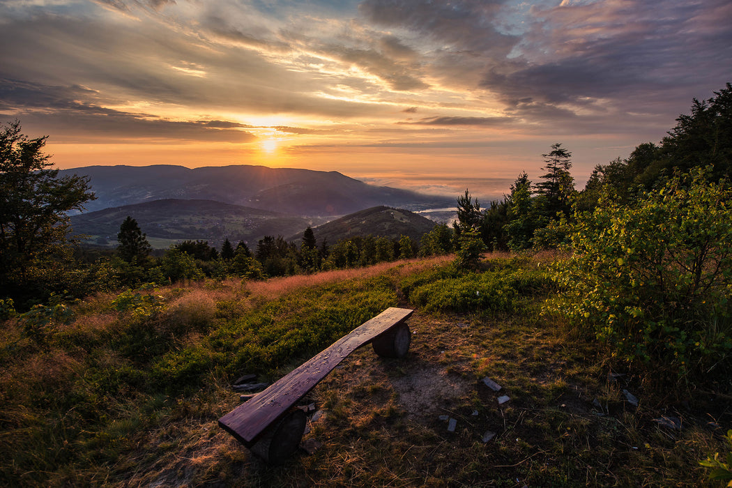 Bank auf Berggipfel bei Sonnenuntergang, Glasbild