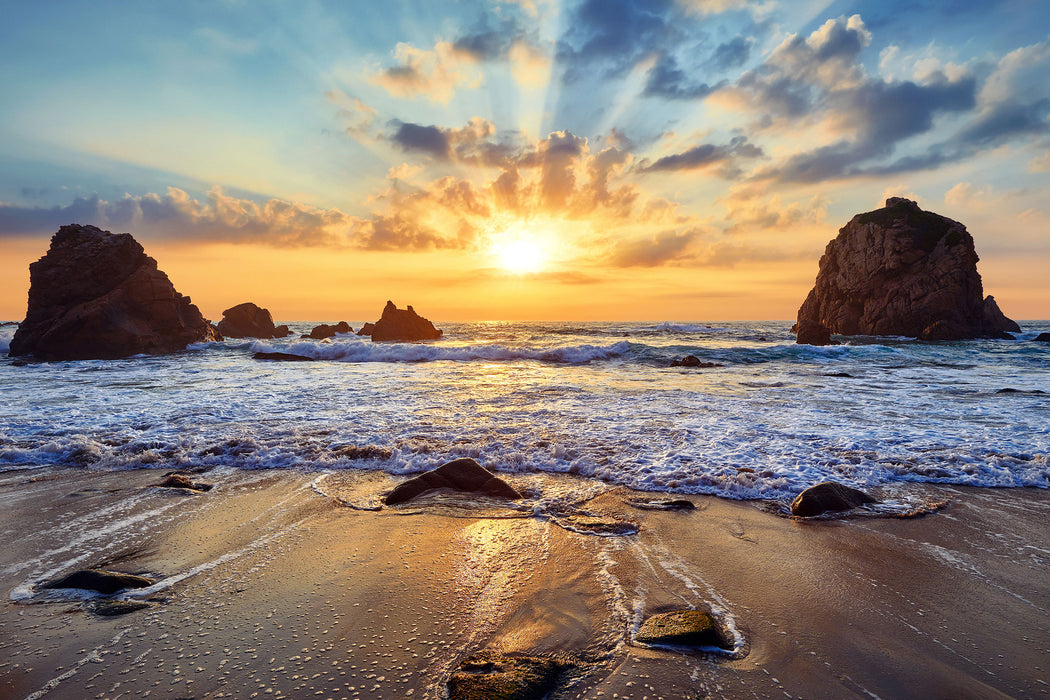 Sandstrand mit Felsen im Sonnenuntergang, Glasbild