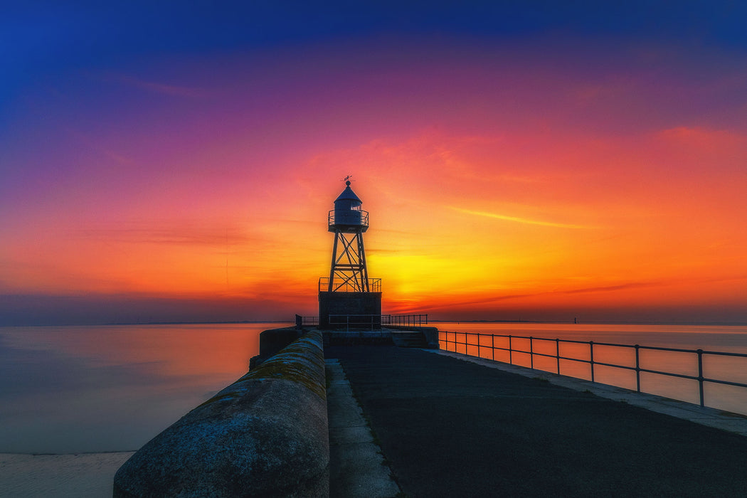 Leuchtturm am Steg bei Sonnenuntergang, Glasbild