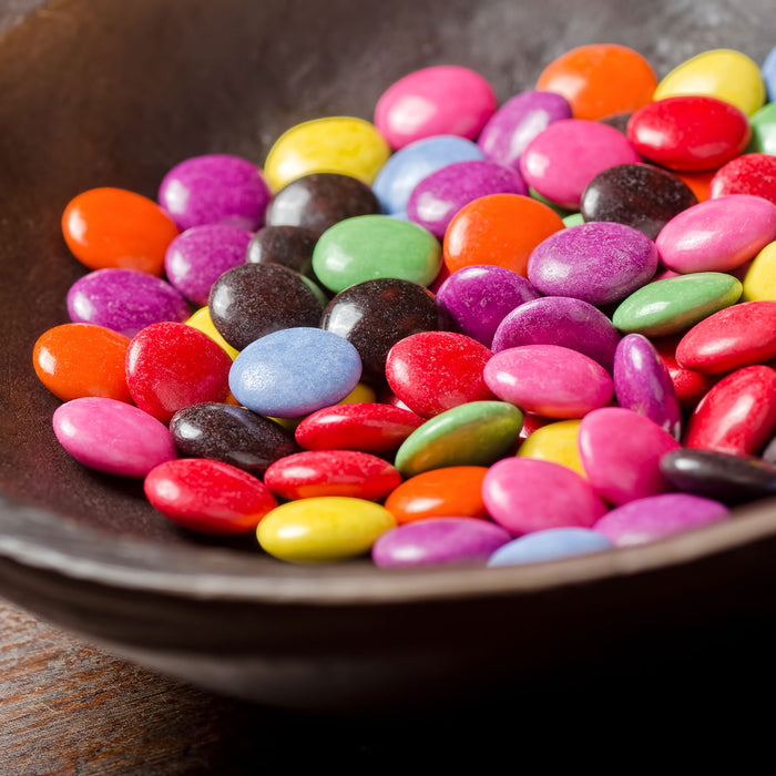 Schokolinsen in Schale, Glasbild Quadratisch