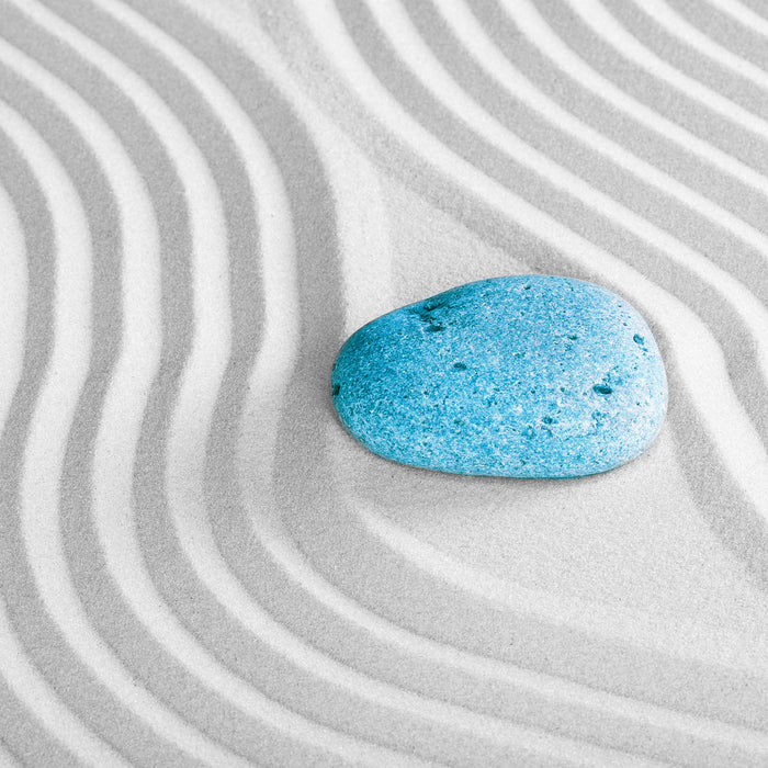 Ein Stein im Sand mit Wellenmuster, Glasbild Quadratisch
