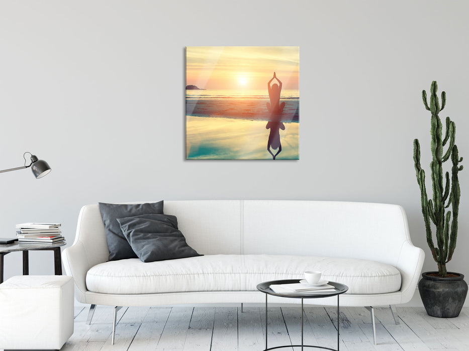 Frau in einer Yogapose am Strand, Glasbild Quadratisch