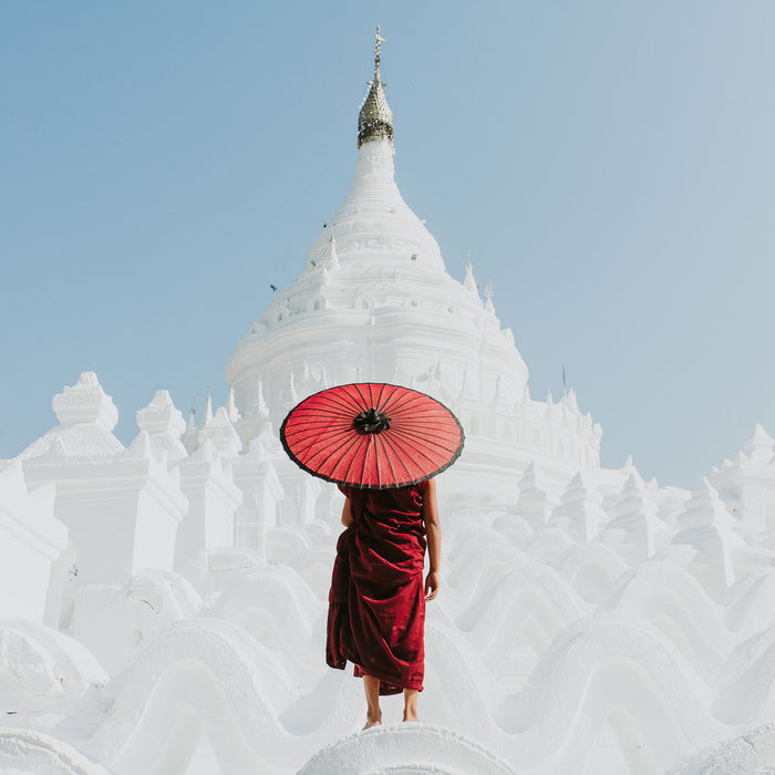 Mönch in rotem Gewand vor weißem Tempel, Glasbild Quadratisch