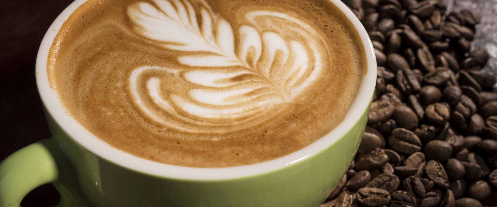 Cappucino zwischen Kaffeebohnen, Glasbild Panorama