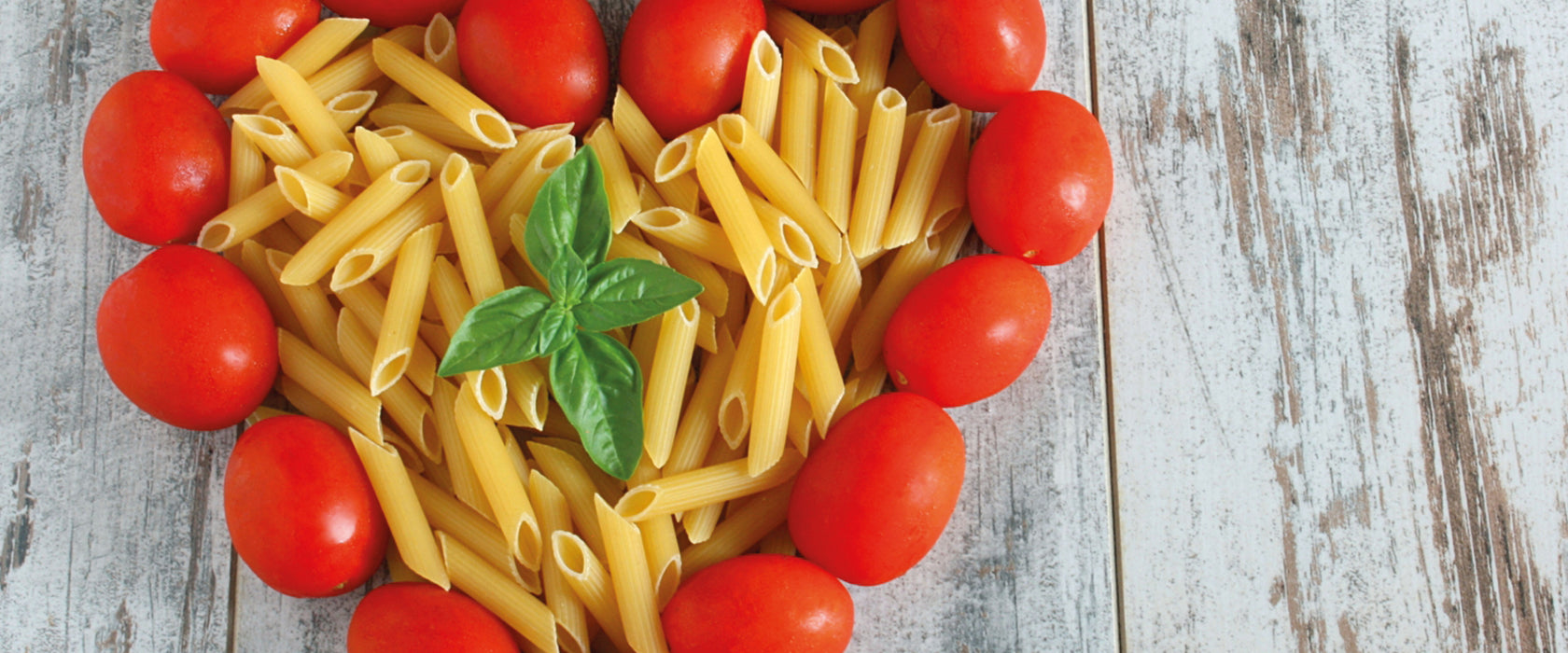 Nudelherz mit Tomaten umrandet, Glasbild Panorama
