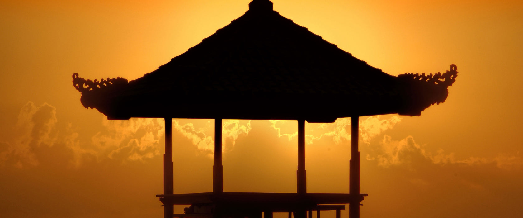 Pagode in Bali im Sonnenuntergang, Glasbild Panorama