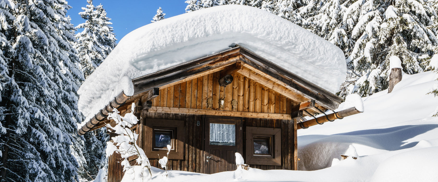 Verschneite Skihütte in Alpenwald, Glasbild Panorama