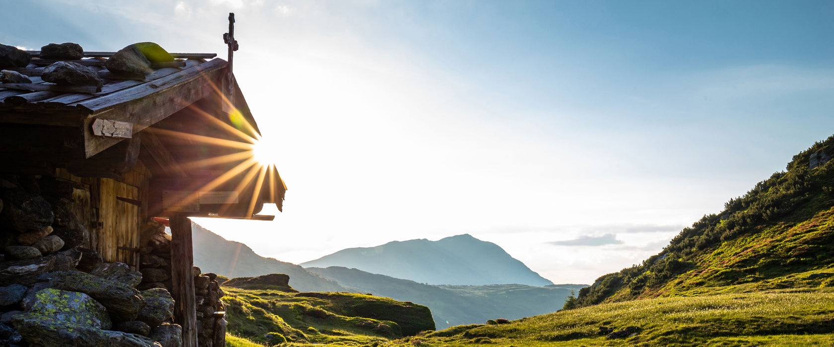 Almhütte am Bach bei Sonnenuntergang, Glasbild Panorama