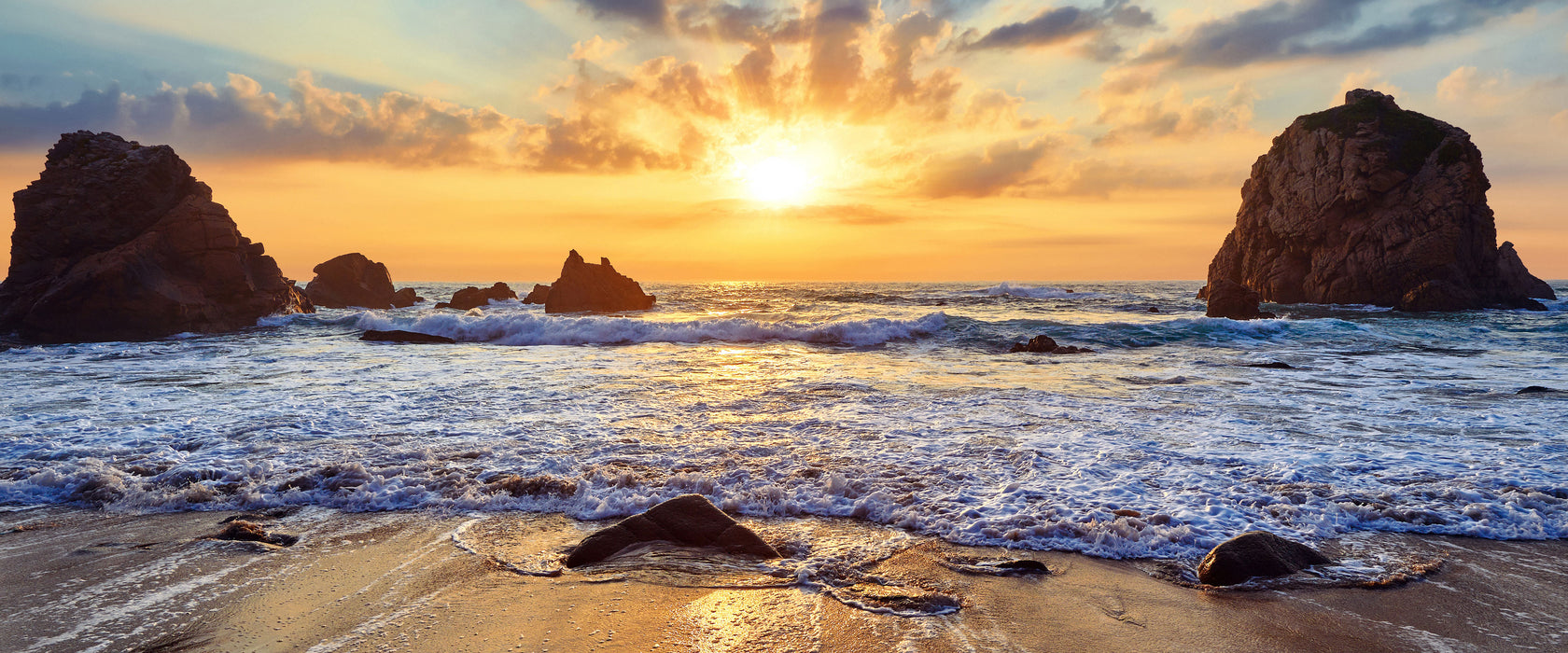 Sandstrand mit Felsen im Sonnenuntergang, Glasbild Panorama