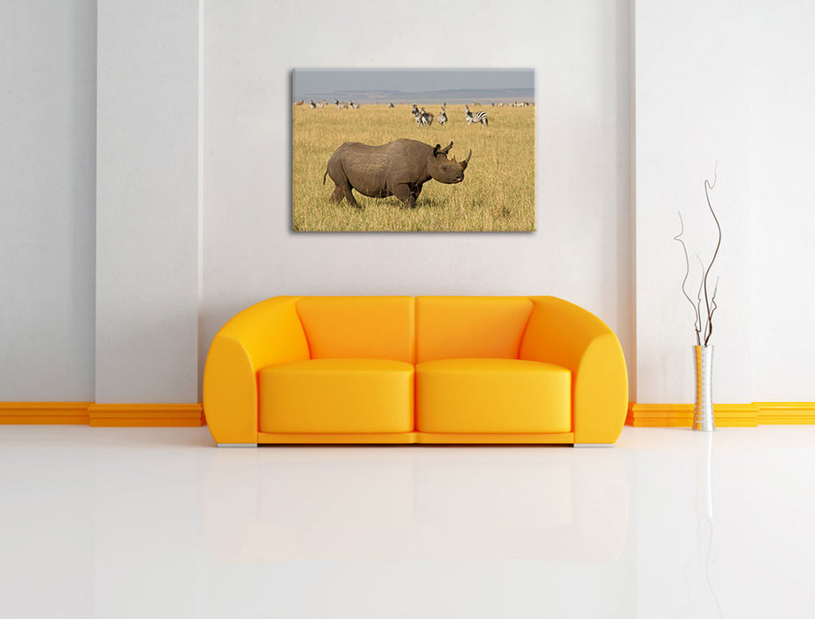 großes Nashorn mit Zebrahorde Leinwandbild über Sofa